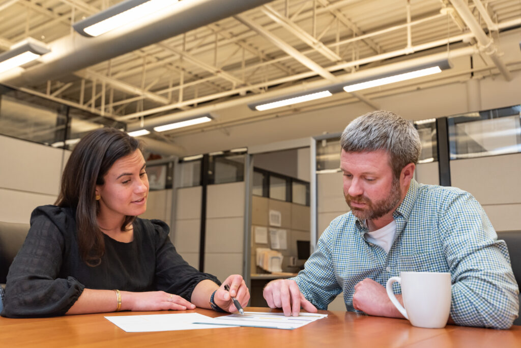 Man and a woman sitting at a table looking at a piece of paper together